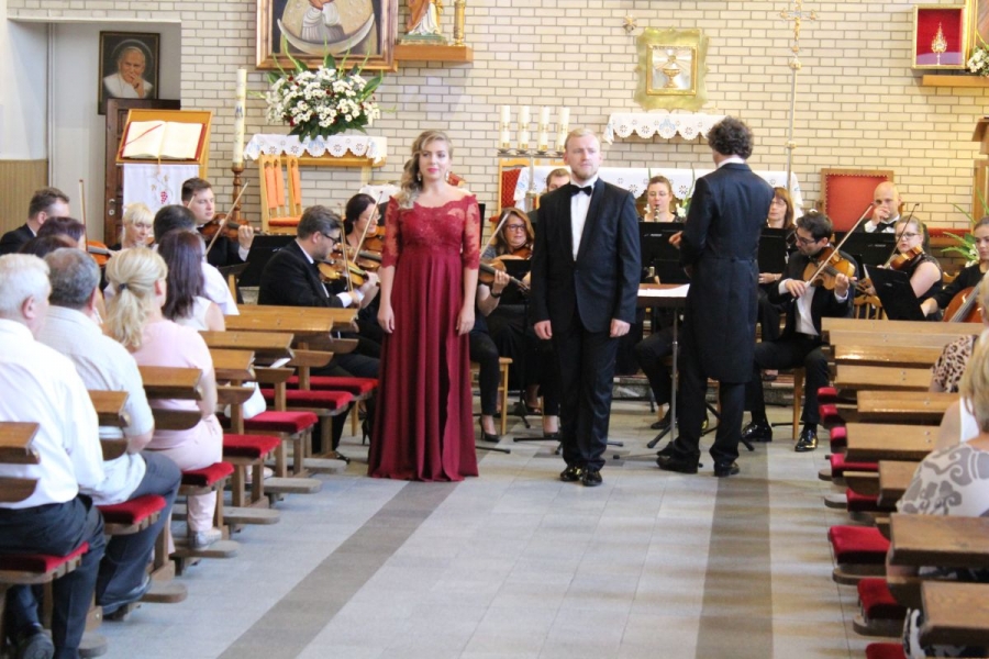 Na pierwszym planie soliści, w tle orkiestra.