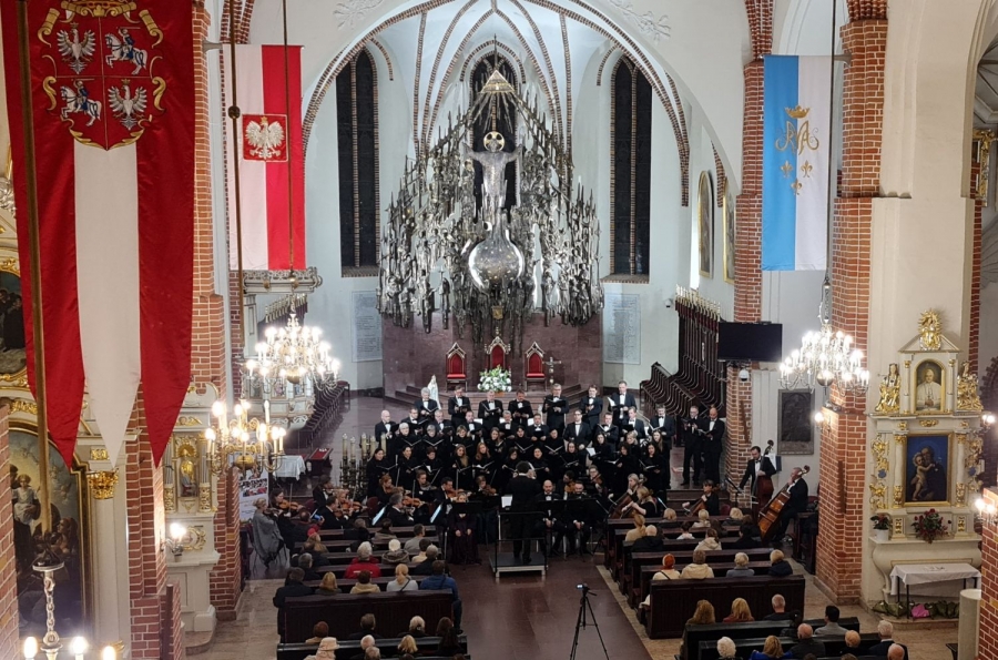 Widok z góry na chór śpiewający w kościele przed ołtarzem.