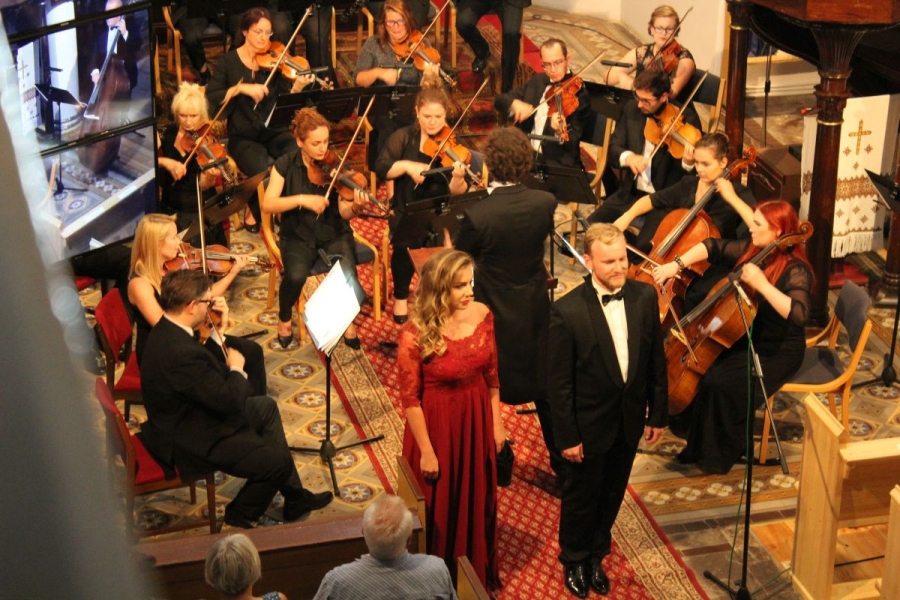 Widok z góry na orkiestrę i solistów. Solistka czerwonej sukni.