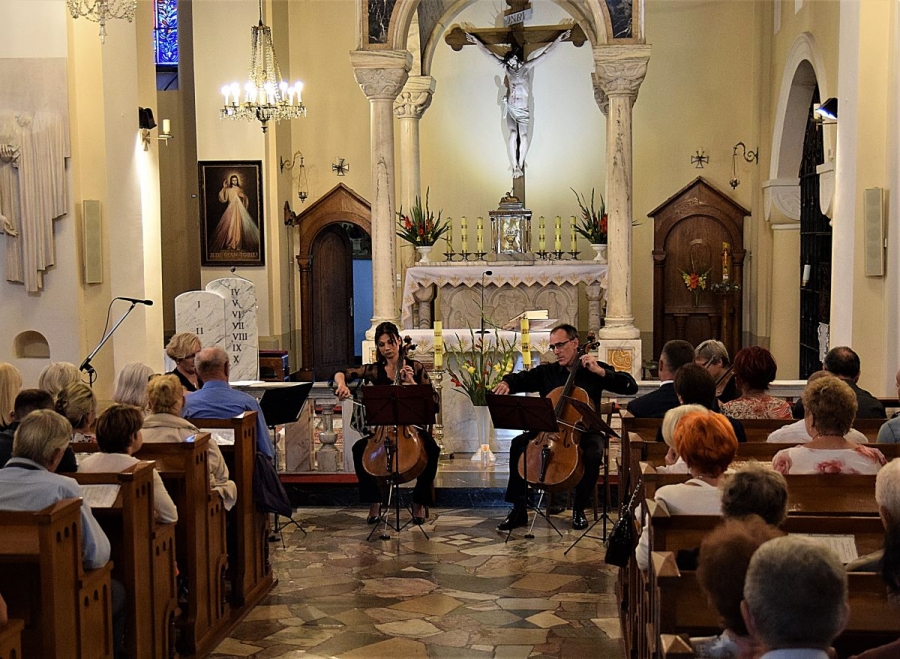 Kwartet wiolonczelowy oraz publiczność w kościele podczas koncertu.