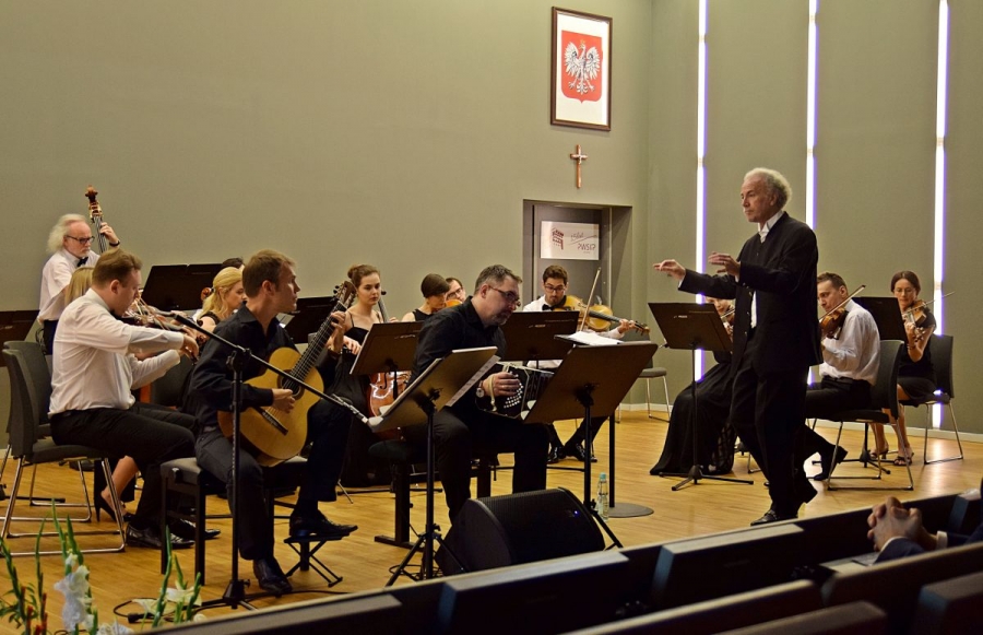 Widok z boku na orkiestrę oraz dyrygenta podczas występu.